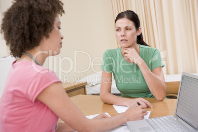 Doctor with laptop and woman in doctor's office frowning