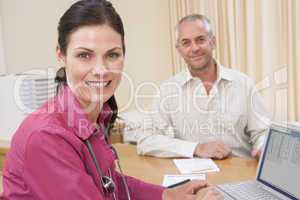 Doctor with laptop and man in doctor's office smiling