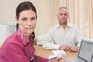 Doctor with laptop and man in doctor's office frowning