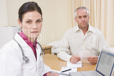 Doctor with laptop and man in doctor's office frowning