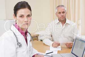 Doctor with laptop and man in doctor's office frowning