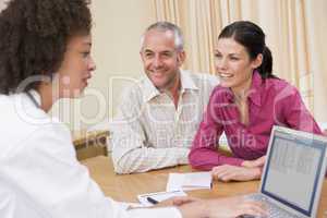 Doctor with laptop and couple in doctor's office smiling