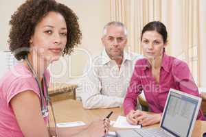 Doctor with laptop and couple in doctor's office