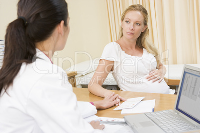 Doctor with laptop and pregnant woman in doctor's office