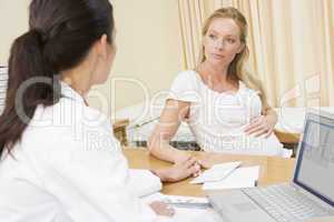 Doctor with laptop and pregnant woman in doctor's office