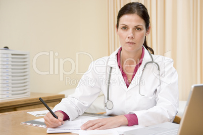 Doctor with laptop writing in doctor's office