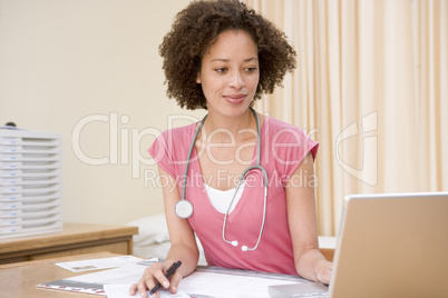 Doctor using laptop in doctor's office smiling