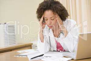 Doctor with laptop and headache in doctor's office