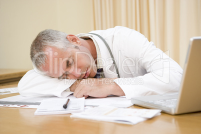 Doctor with laptop sleeping in doctor's office