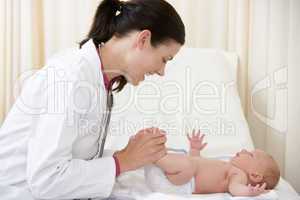 Doctor giving checkup to baby in exam room smiling