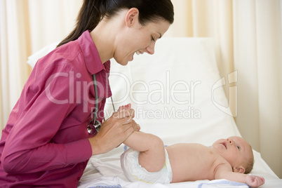 Doctor giving checkup to baby in exam room smiling