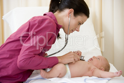 Doctor giving checkup with stethoscope to baby in exam room