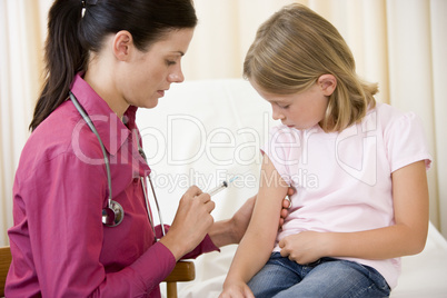 Doctor giving needle to young girl in exam room