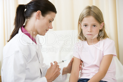 Doctor giving needle to young girl in exam room