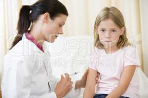 Doctor giving needle to young girl in exam room