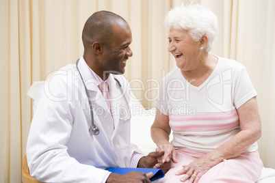 Doctor giving checkup to woman in exam room smiling