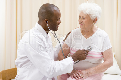 Doctor giving checkup with stethoscope to woman in exam room smi