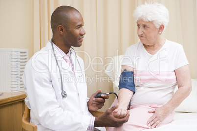 Doctor checking woman's blood pressure in exam room