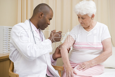 Doctor giving needle to woman in exam room