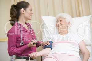 Doctor checking woman's blood pressure in exam room smiling