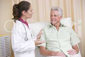 Doctor giving checkup to man in exam room smiling