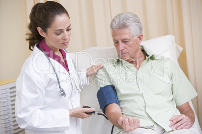 Doctor checking man's blood pressure in exam room