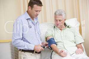 Doctor checking man's blood pressure in exam room