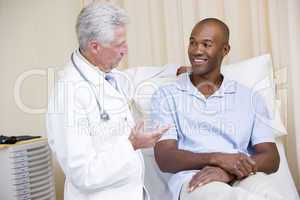 Doctor giving smiling man checkup in exam room