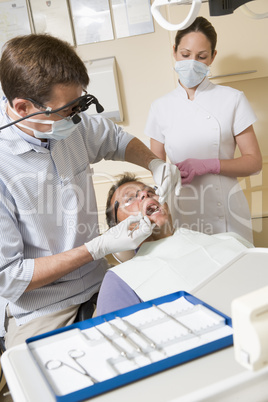 Dentist and assistant in exam room with man in chair