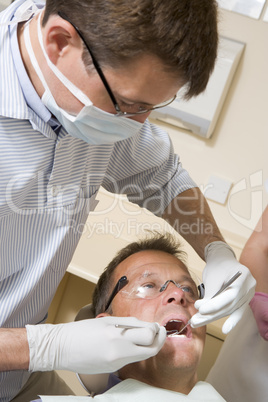 Dentist and assistant in exam room with man in chair