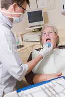 Dentist in exam room with woman in chair