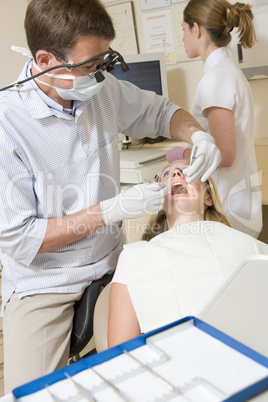 Dentist and assistant in exam room with woman in chair