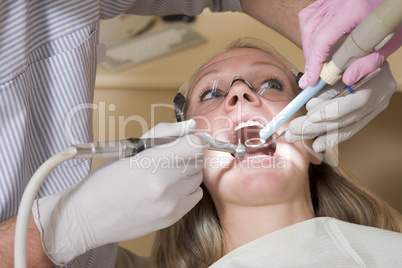 Dentist and assistant in exam room with woman in chair