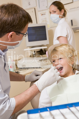 Dentist and assistant in exam room with young boy in chair