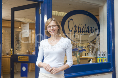 Woman standing at front entrance of optometrists smiling