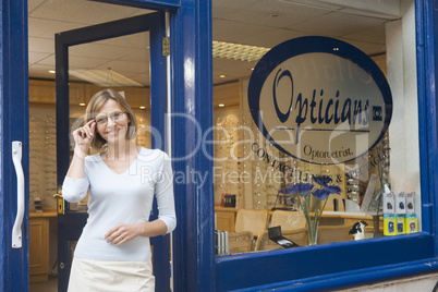 Woman standing at front entrance of optometrists smiling