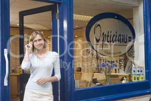 Woman standing at front entrance of optometrists smiling