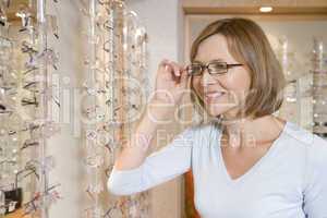 Woman trying on eyeglasses at optometrists smiling