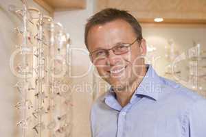 Man trying on eyeglasses at optometrists smiling