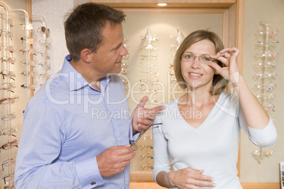 Couple trying on eyeglasses at optometrists smiling