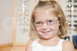 Young girl trying on eyeglasses at optometrists smiling