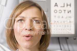 Woman in optometrist's exam room taking deep breath