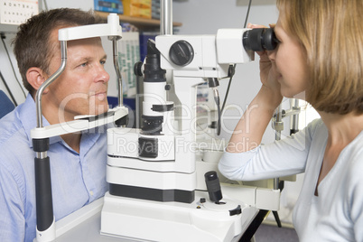 Optometrist in exam room with man in chair