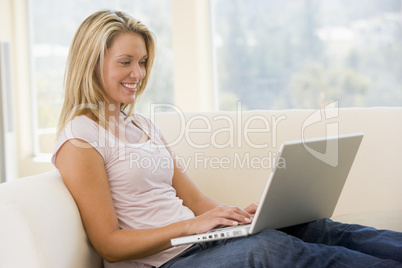 Woman in living room using laptop smiling