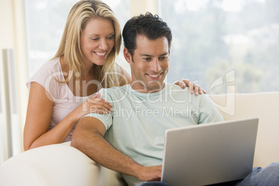 Couple in living room using laptop smiling