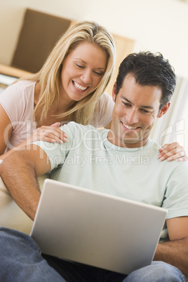 Couple in living room using laptop smiling