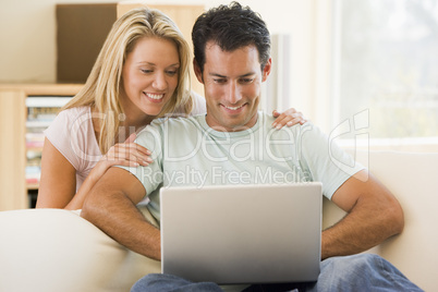 Couple in living room using laptop smiling