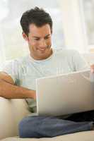 Man in living room using laptop smiling