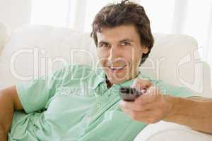 Man in living room holding remote control smiling