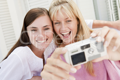Two women on patio using digital camera smiling